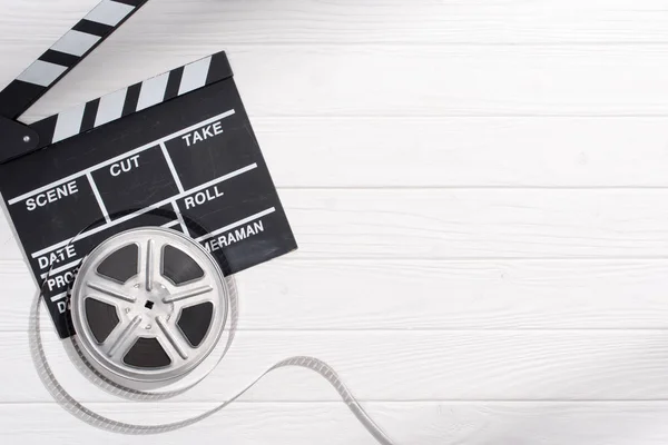 Flat lay with clapper board and filmstrips on white wooden tabletop — Stock Photo