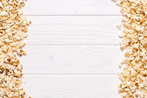 Cornice completa di popcorn disposti su tavolo in legno bianco — Foto stock