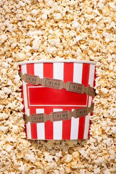 Flat lay with disposable bucket, crunchy popcorn and retro cinema tickets — Stock Photo