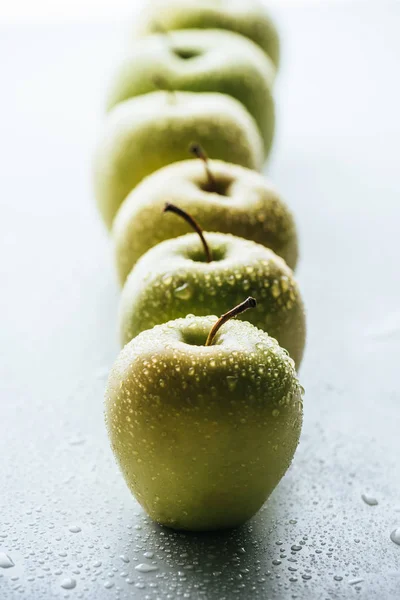 Vista de cerca de manzanas verdes con gotas de agua sobre fondo blanco - foto de stock