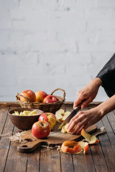 Plan recadré de femme coupant des pommes sur planche à découper en bois — Photo de stock