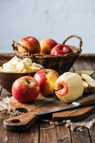 Vista de cerca de manzanas peladas, cortadas y sanas en la tabla de cortar en la superficie de madera oscura - foto de stock