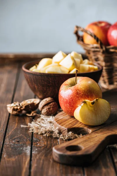 Vista de cerca de manzanas cortadas y sanas en la tabla de cortar en la superficie de madera oscura - foto de stock