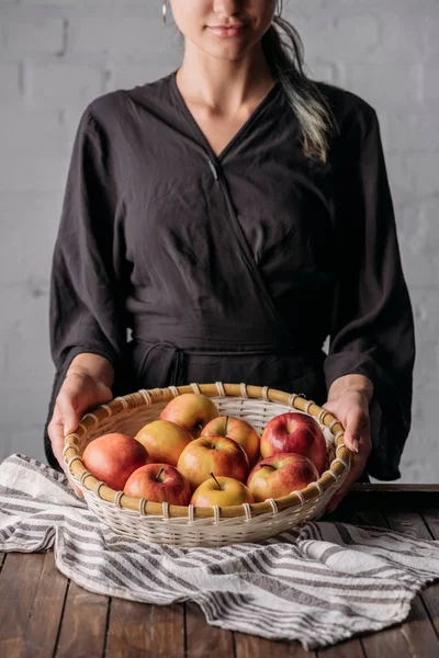 Visão parcial da mulher segurando cesta com maçãs frescas — Fotografia de Stock