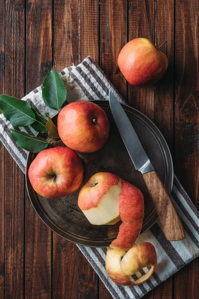 Tendido plano con manzanas maduras y cuchillo en bandeja de metal sobre mesa de madera — Stock Photo