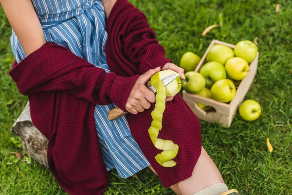 Vista recortada de niña pelando manzanas verdes con cuchillo - foto de stock