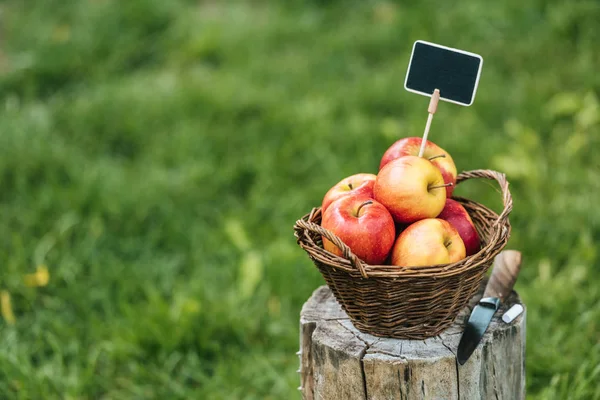 Manzanas rojas frescas recogidas en canasta de mimbre con etiqueta para la venta - foto de stock