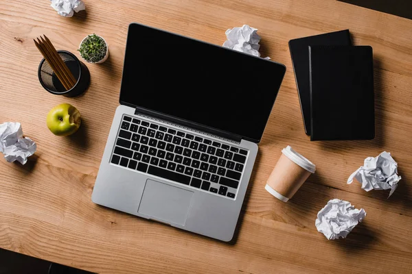 Vista superior do local de trabalho bagunçado com laptop e papéis amassados — Fotografia de Stock