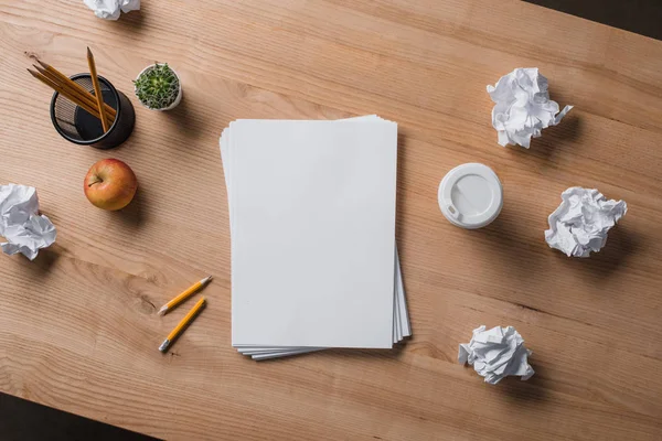 Top view of stacked blank papers on wooden table with crumpled papers — Stock Photo