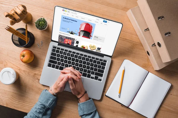 Обрезанный снимок бизнесмена, сидящего на рабочем месте с ноутбуком, веб-сайт ebay на экране — стоковое фото