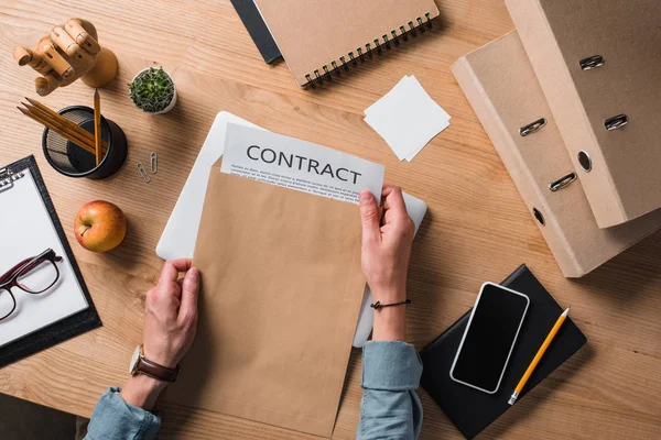 Cropped shot of businessman taking contract from envelope at workplace — Stock Photo