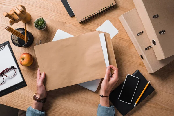 Recortado disparo de empresario sosteniendo sobre con documentos en el lugar de trabajo - foto de stock