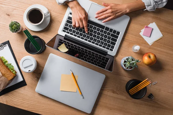 Cropped shot of businesswoman sitting at workplace with laptops and typing — Stock Photo