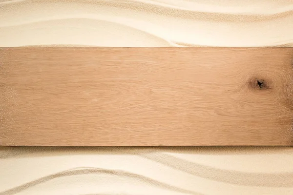 Vue du dessus de la planche de bois vierge sur une surface sablonneuse — Photo de stock