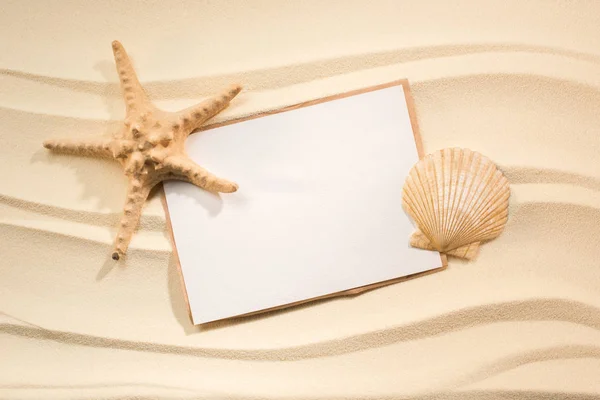 Plat avec étoile de mer, coquillage et papier blanc sur sable — Photo de stock