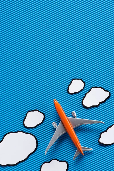 Vista superior del avión de juguete y nubes de papel sobre fondo azul, concepto de viaje - foto de stock