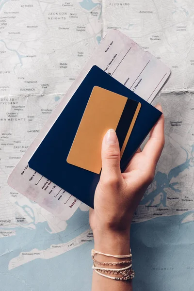 Foto recortada de la mujer con pasaporte, billete y tarjeta de crédito en la mano con el mapa en el fondo, concepto de vacaciones - foto de stock