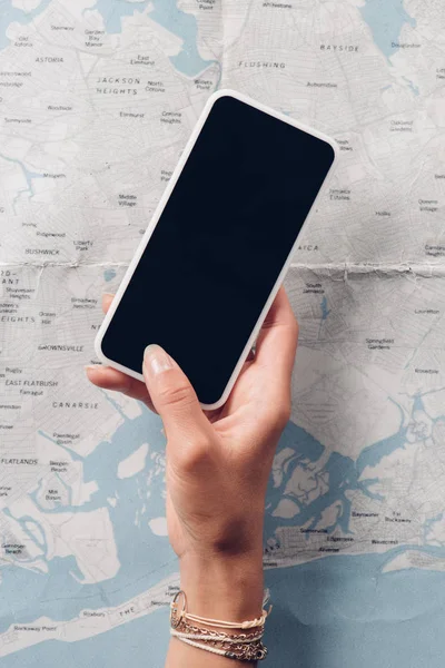 Vue partielle de la femme tenant smartphone avec écran blanc avec carte en arrière-plan, concept de voyage — Photo de stock