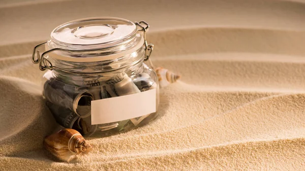 Close up view of glass jar with dollars on sandy beach with seashells, traveling concept — Stock Photo