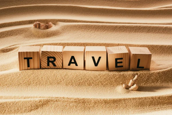 Close up view of wooden blocks with travel inscription on sandy beach — Stock Photo