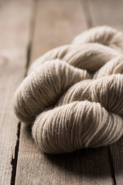 Fuoco selettivo di palline di filato di lana lavorate a maglia beige su sfondo di legno — Foto stock