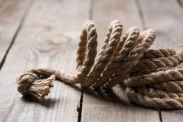 Selective focus of beige knotted nautical rope on wooden background — Stock Photo