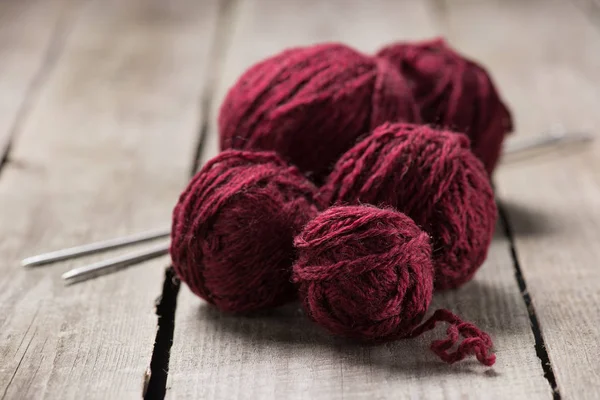 Selective focus of red knitted yarn balls and knitted needles on wooden background — Stock Photo