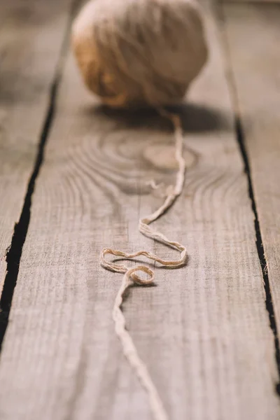 Foyer sélectif de boule de fil tricoté beige démêlé sur fond en bois — Photo de stock