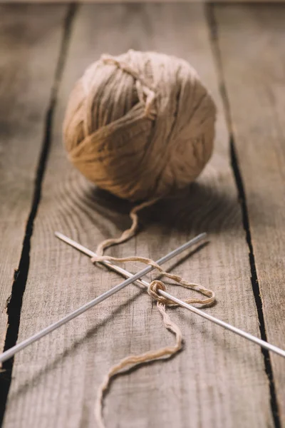 Selective focus of beige knitted woolen yarn ball and knitted needles on wooden background — Stock Photo