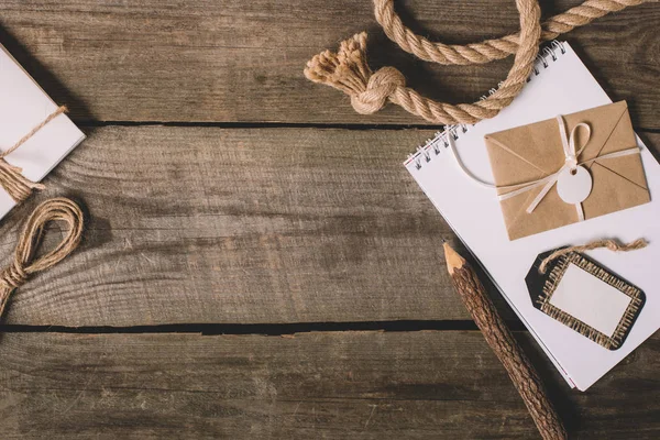 Top view blank textbook, wrapped letter, tree pencil and nautical rope on wooden background — Stock Photo