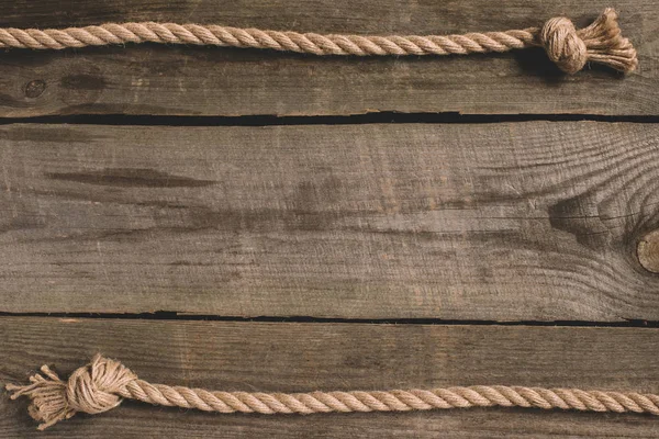 Top view of beige knotted nautical rope on wooden background — Stock Photo