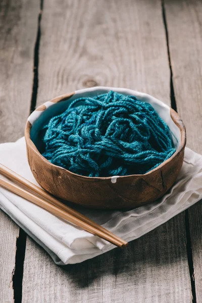 Selective focus of knitting needles, bowl with untangled knitting yarn and sackcloth on wooden background — Stock Photo