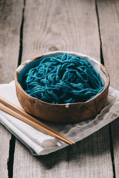 Enfoque selectivo de agujas de punto, tazón con hilo de punto desenredado y tela de saco sobre fondo de madera — Stock Photo