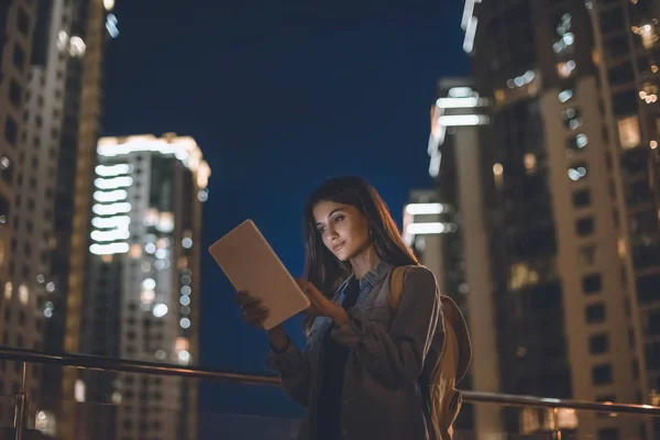 Боковой вид привлекательной женщины с помощью цифрового планшета на улице города ночью — стоковое фото