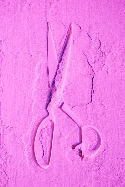 Top view of scissors shape on pink colored flour texture — Stock Photo