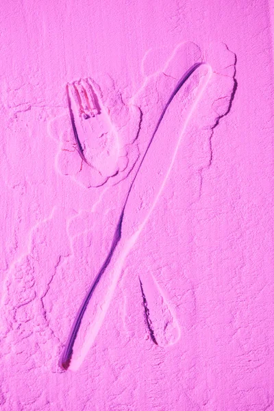 Shape of knife and fork on pink colored flour — Stock Photo
