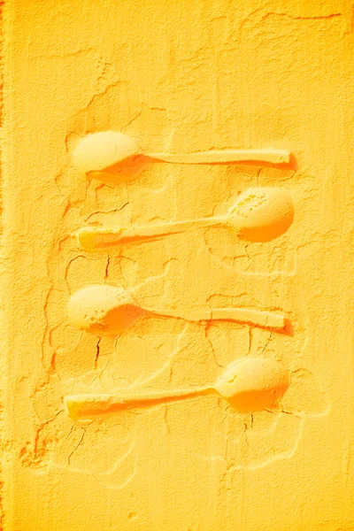 Top view of spoons shapes on bright orange flour texture — Stock Photo