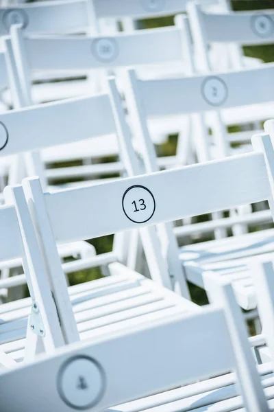 Vue rapprochée des chaises blanches vides avec numéros sur pelouse verte — Photo de stock