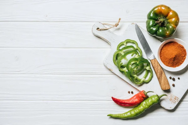 Top view of chili and bell peppers, bowl with spice on white wooden table — Stock Photo