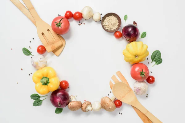 Top view of circle of ripe vegetables and wooden spatulas isolated on white — Stock Photo