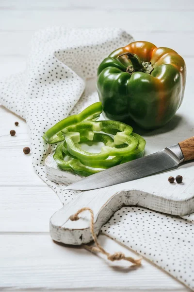 Ripe cut and whole bell peppers on white wooden board — Stock Photo