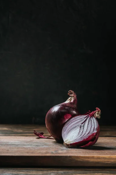 Cebolla roja cortada madura en tabla de cortar aislada en negro - foto de stock