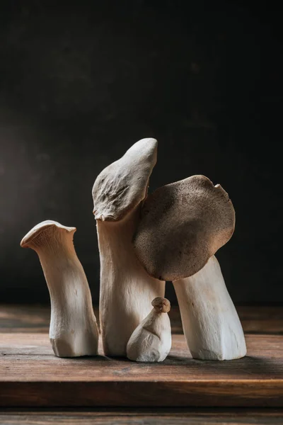 Ripe king trumpet mushrooms on wooden cutting board isolated on black — Stock Photo