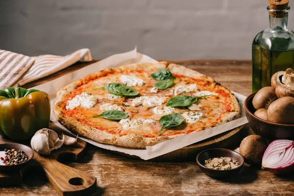 Close up view of delicious italian pizza and ingredients on wooden surface — Stock Photo