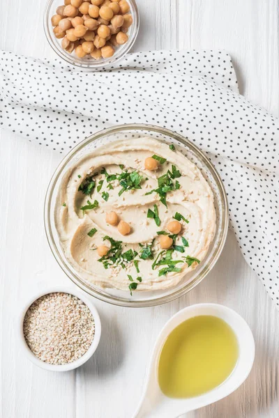 Top view of hummus with parsley, chickpeas and olive oil on wooden tabletop — Stock Photo