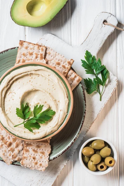 Top view of hummus with parsley, olives, pita bread and avocado on wooden tabletop — Stock Photo