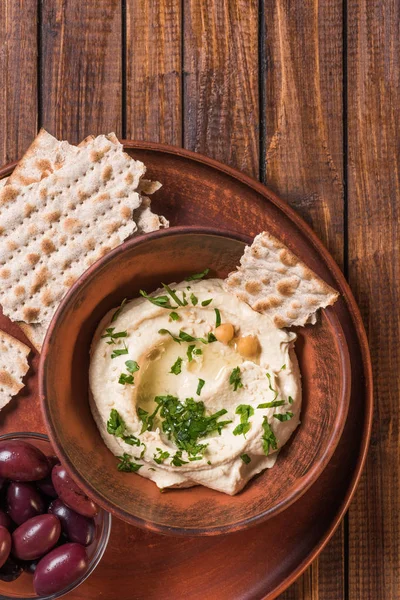 Top view of olives, pita bread and hummus with parsley and chickpeas in bowl on wooden surface — Stock Photo