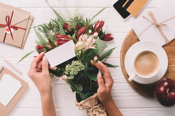 Vista parcial da mulher com cartão em branco na mesa com buquê de flores, xícara de café e cartão de crédito — Fotografia de Stock