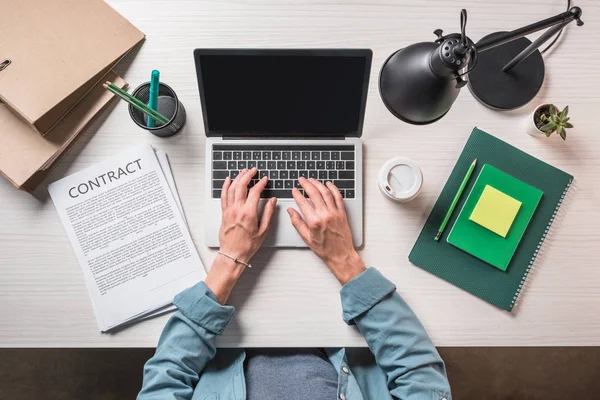 Cropped image of businessman using laptop at table with contract, stationery and coffee — Stock Photo