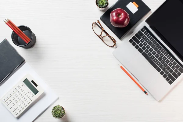 Erhöhte Sicht auf den Arbeitsplatz mit Schreibwaren, Brille, Taschenrechner und Laptop auf dem Tisch — Stockfoto